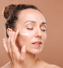 Mujer de mediana edad aplicandose crema facial